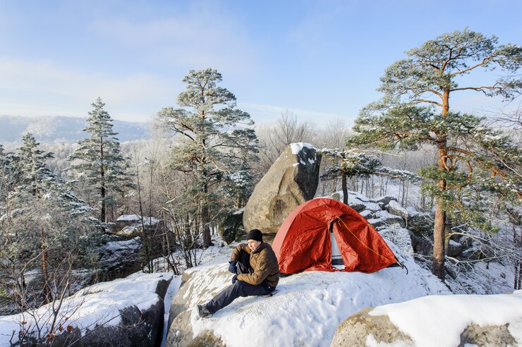 Photo male climber nearly his tent on the top of rock