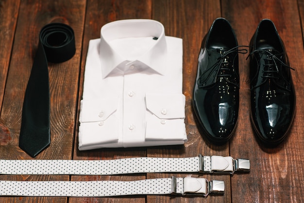 Male clothes set. Shirt tie shoes and suspenders on wooden desk