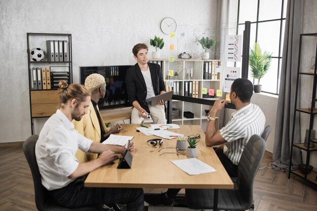 Foto lavoratore di società maschile in abbigliamento formale seduto alla scrivania in ufficio e ascoltando il caposquadra