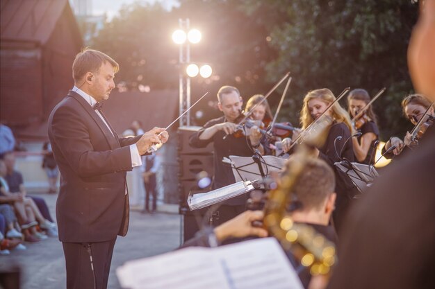 Foto direttore d'orchestra maschio che dirige l'esibizione dell'orchestra per strada