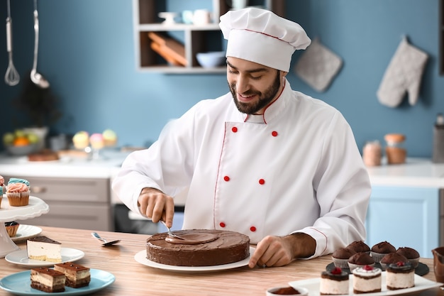 Photo male confectioner decorating tasty chocolate cake in kitchen
