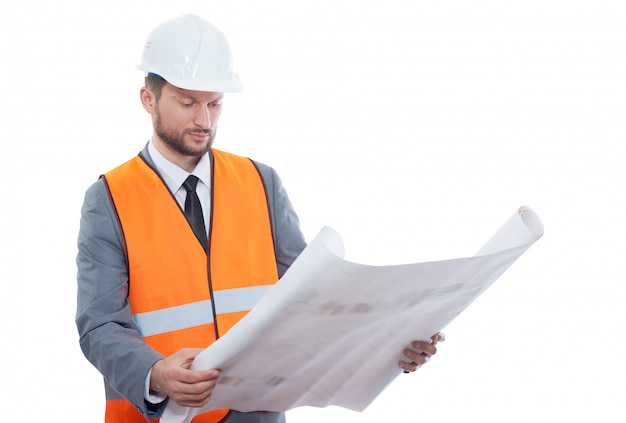 Male construction worker wearing protective helmet and safety vest examining building .