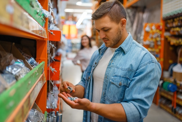 Male consumer choosing nuts in hardware store.