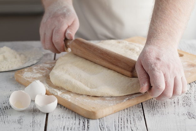 male cook rolling out dough on the table