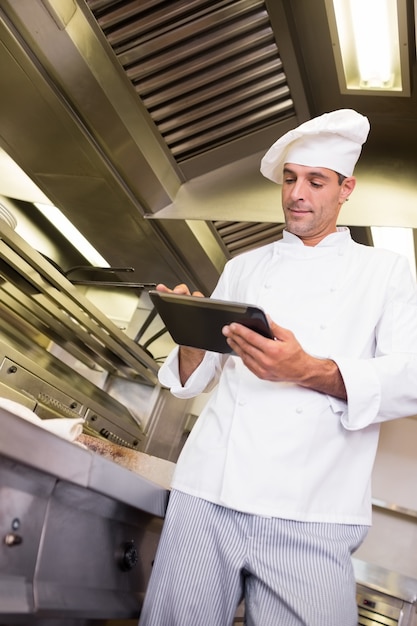 Male cook using digital tablet in kitchen