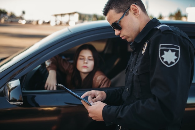 Il poliziotto in uniforme scrive una multa al conducente donna