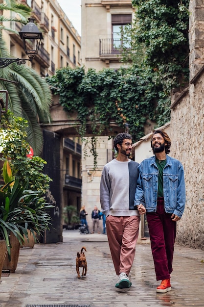 Male couple walking with dog in a beautiful street