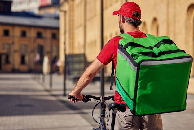 Foto corriere maschio con borsa frigo in bicicletta