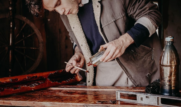мужчина-мастер лакирует деревянную мебель ручной работы