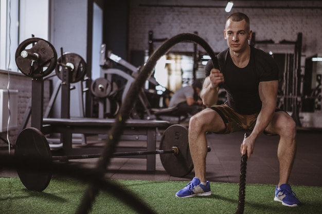 ジムでバトルロープでワークアウト男性crossfitアスリート