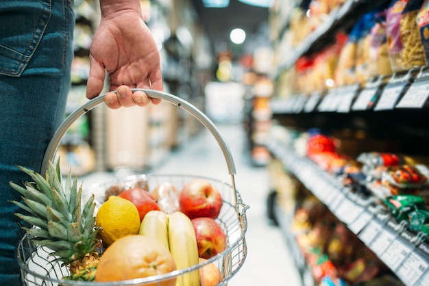 果物のバスケット、スーパーマーケットで食品を選択する人々と男性客の手。食料品店でのショッピング