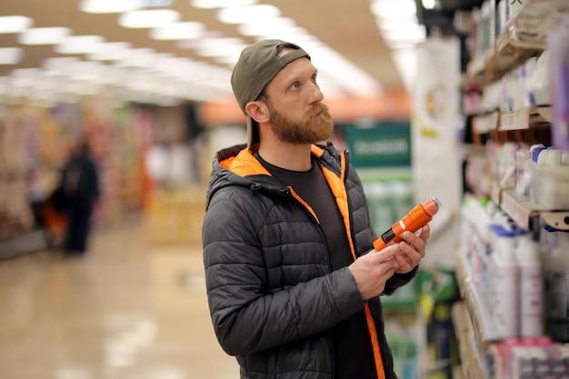 A male customer is interested in an orange colored deodorant spray bottle at the grocery store for o