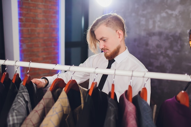 Male customer looking for a jacket in men clothes store.