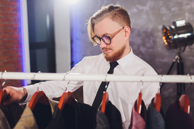 Male customer looking for a jacket in men clothes store.