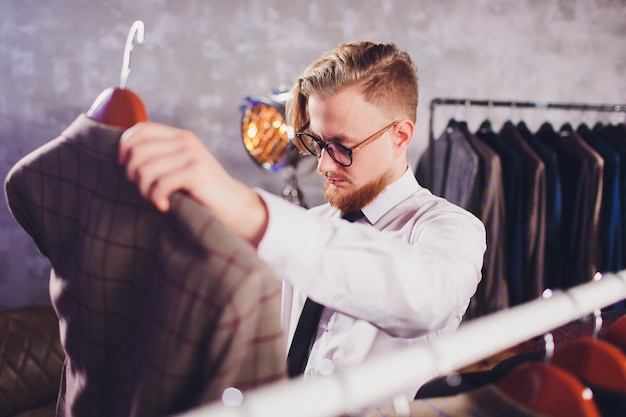 Male customer looking for a jacket in men clothes store.