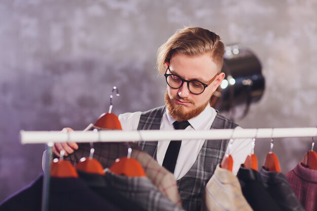 Male customer looking for a jacket in men clothes store.