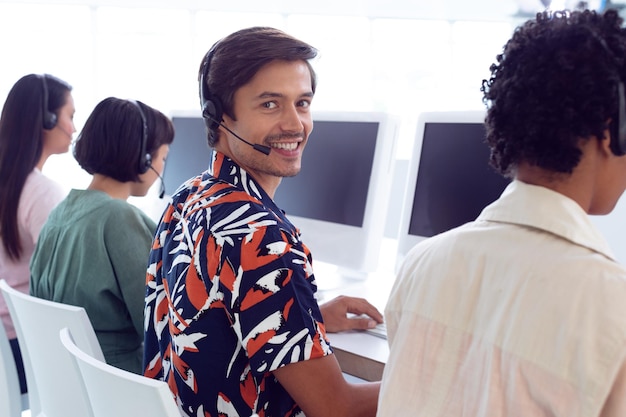 Male customer service executive working on computer at desk in office