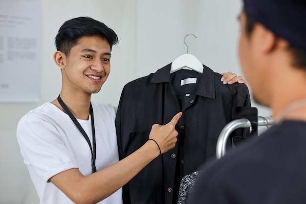 Мужской клиент, покупающий в магазине одежды, помощник розничного продавца помогает с советами