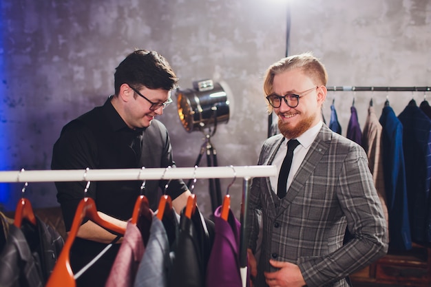 Мужской клиент в торговом центре пробует деловую одежду с помощью продавца