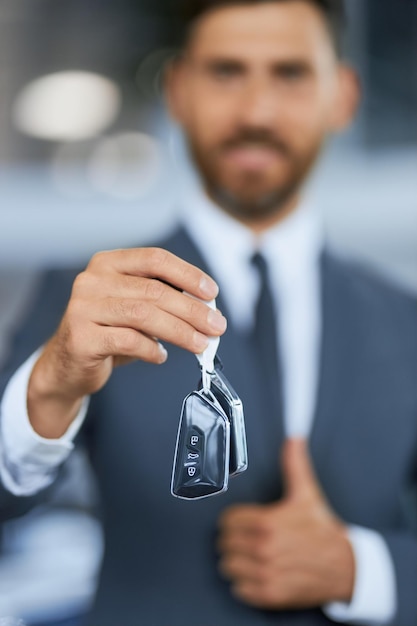 Male customer standing at car salon and holding keys