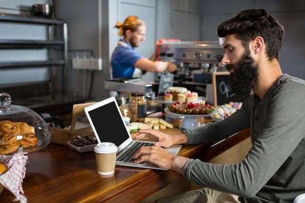 Photo male customer using laptop while having coffee at counter