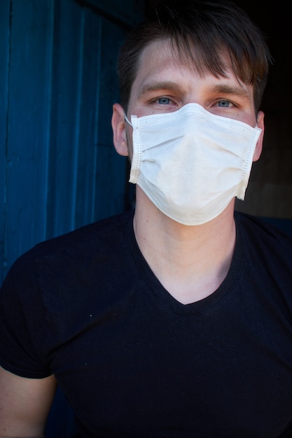 医療マスクの暗い背景の男性。ウイルス、バクテリア、病気からの保護