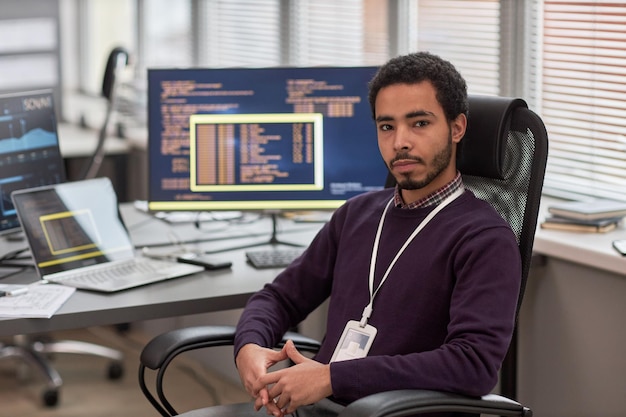 Male data scientist looking at camera while sitting at desk in office