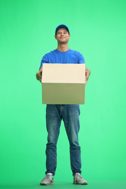 Мужчина-доставщик на зеленом фоне полной длины с коробкой