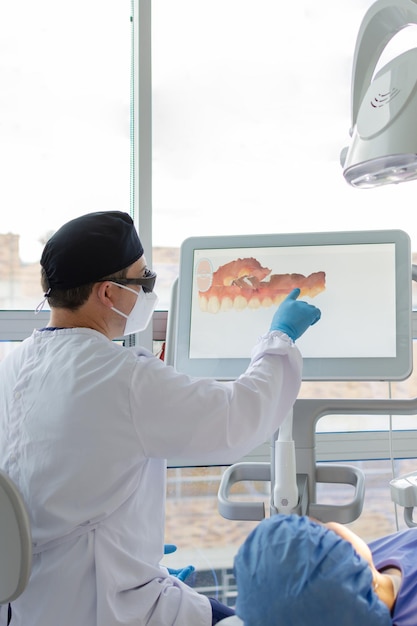 Male dentist analyzing a virtual model of a female patient