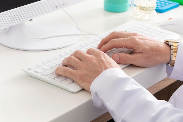 Male dentist doctor hands on computer keyboard