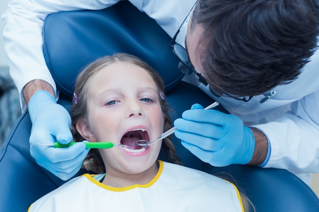 Male dentist examining girls teeth