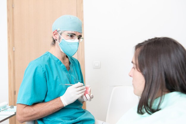 偽の歯列を使用して患者に状況を説明する男性の歯科医
