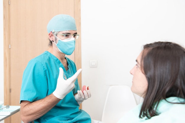 Male dentist explaining the situation to a patient with double mask during coronavirus pandemic