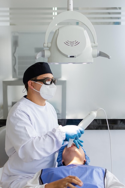 Male dentist performing a scan for the 3d model of a female patient39s mouth Dental clinic concept