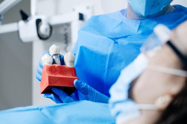 Male dentist showing his female patient a dental implant