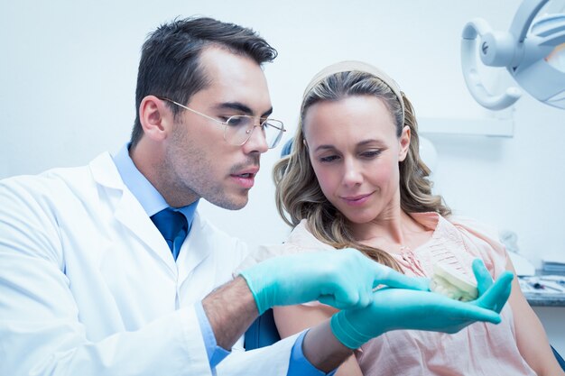 Male dentist showing woman prosthesis teeth