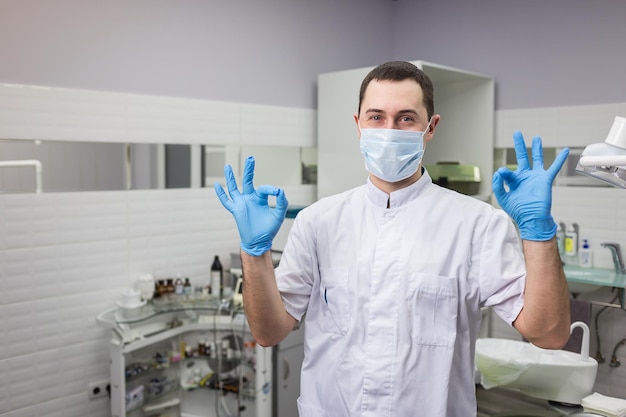 Стоматолог-мужчина, стоящий на фоне медицинского кабинета