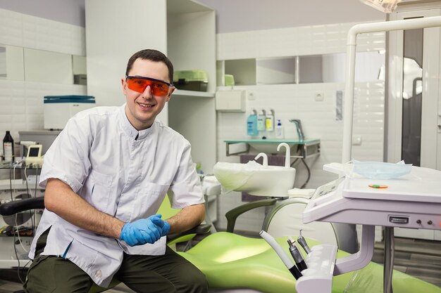 Male dentist standing over medical office background Healthcare profession stomatology and medicine concept