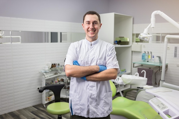 Male dentist standing with his hands crossed over medical office background Healthcare profession stomatology and medicine concept