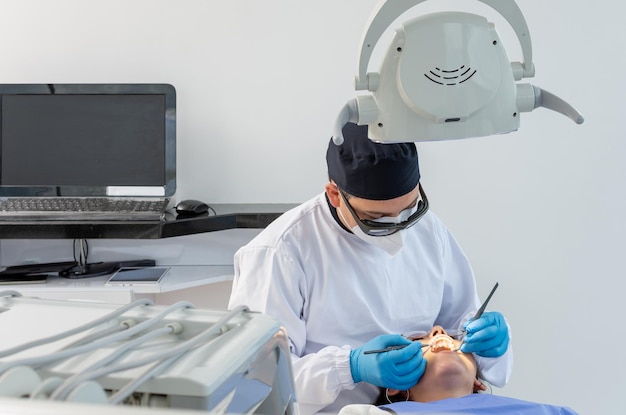 Male dentist in uniform during a dental intervention Dental clinic concept