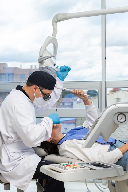 Male dentist in uniform and face mask during a dental
intervention on a woman dental clinic concept