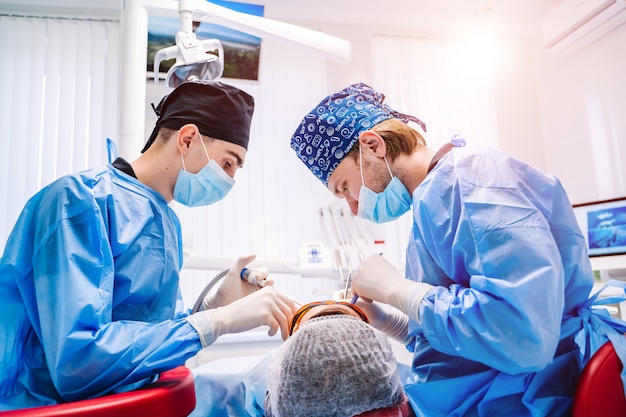 A male dentist in uniform perform dental implantation operation