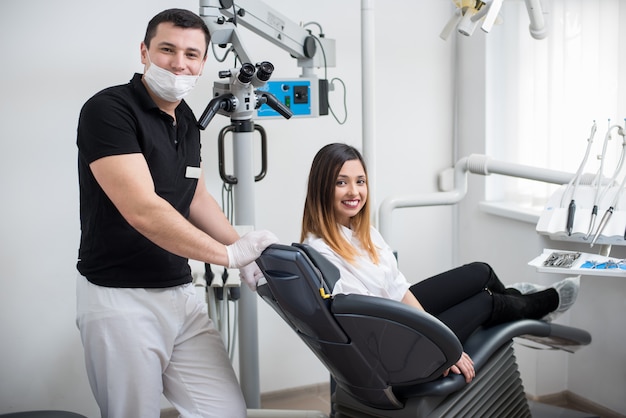 Dentista maschio con il paziente femminile dopo il trattamento in clinica odontoiatrica moderna