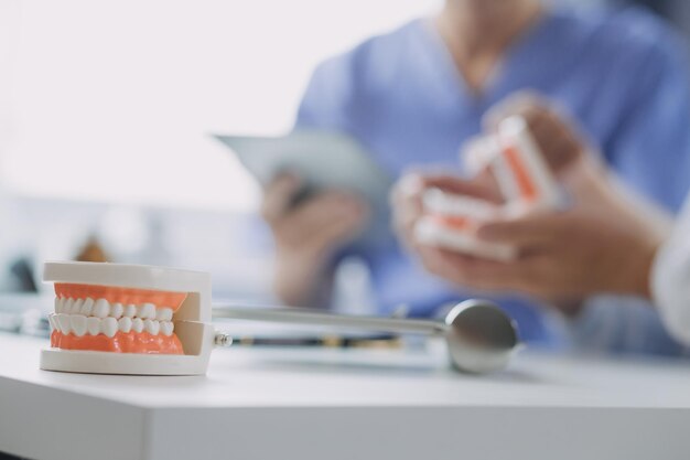 Male dentist with plastic jaw model on light background