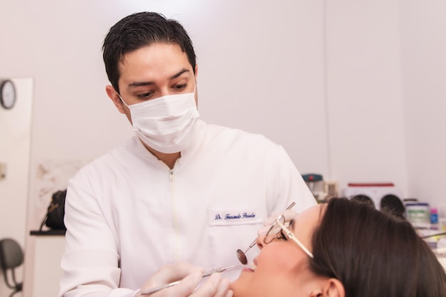 Foto dentista maschio che si occupa della sua paziente femminile nel suo ufficio dentistico.