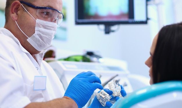 男性の歯科医が若い女性の患者を診察し、作業している歯科医院