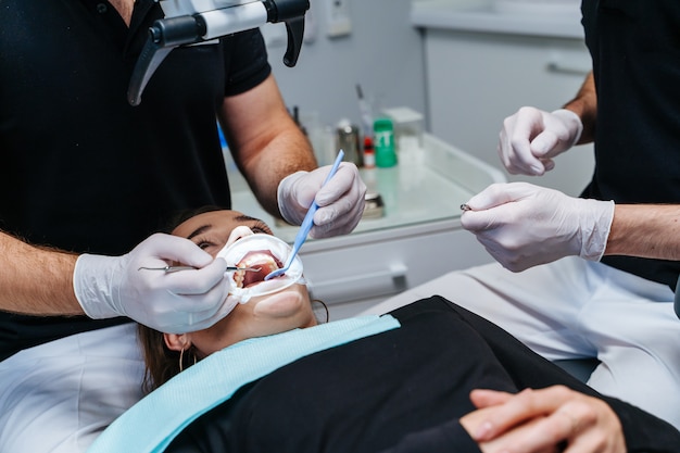 Photo male dentists treating patient's teeth at modern dental clinic office