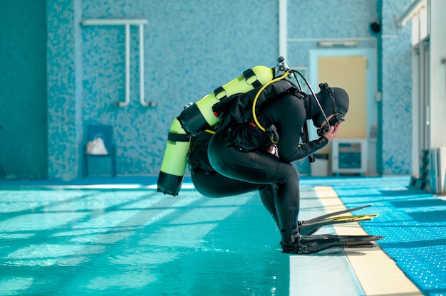 Male divers in scuba gear jump into the pool