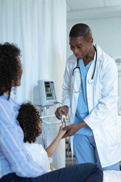 Male doctor attaching pulse oximetry on child patient hand in the ward