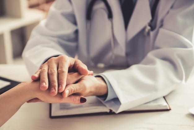 Male doctor calms patient girl in clinic.